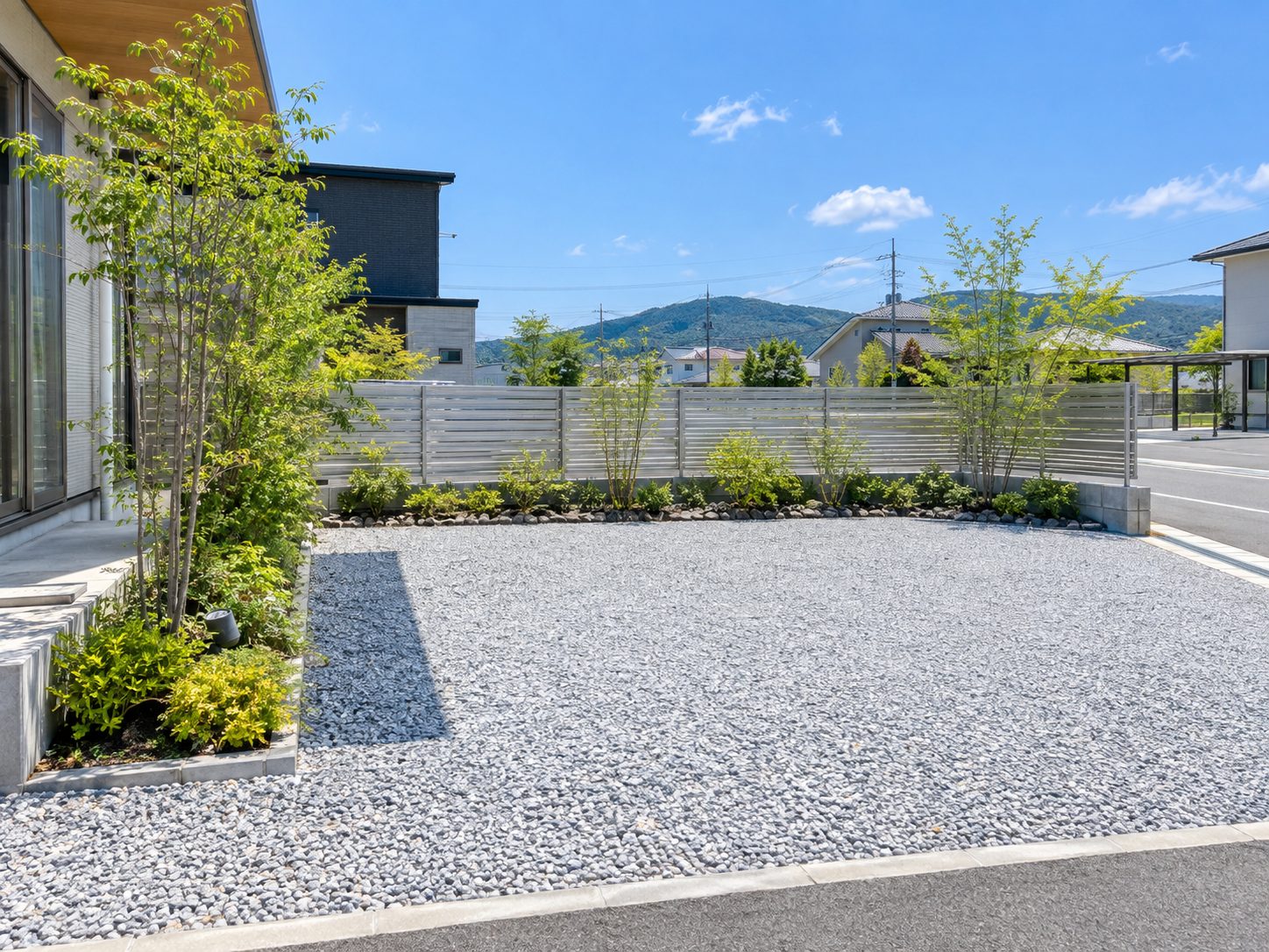砕石を敷いた駐車場と新しいアルミフェンス、植栽のある外構のイメージ